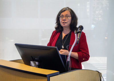 woman behind a podium with computer screen and microphone
