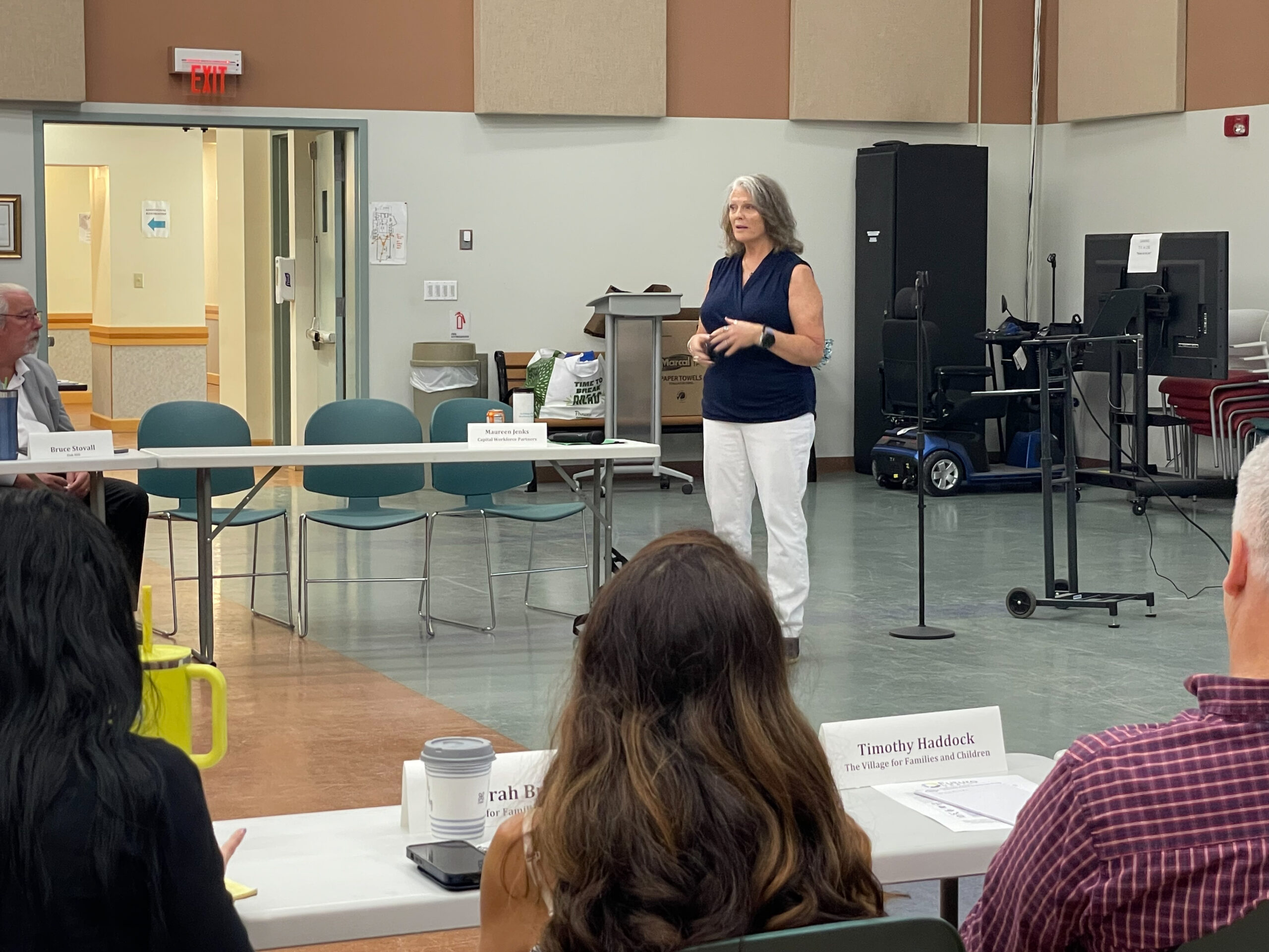 woman standing in front of people, talking