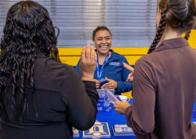 Employer with big smile engaging with two job seekers at TDL Career Fair