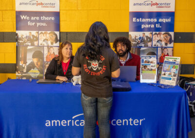Two workforce managers talking to a young adult at TDL Career Fair