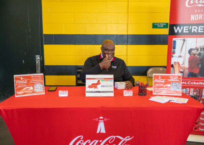 Man giving thumbs up while sitting behind a table at TDL Career Fair