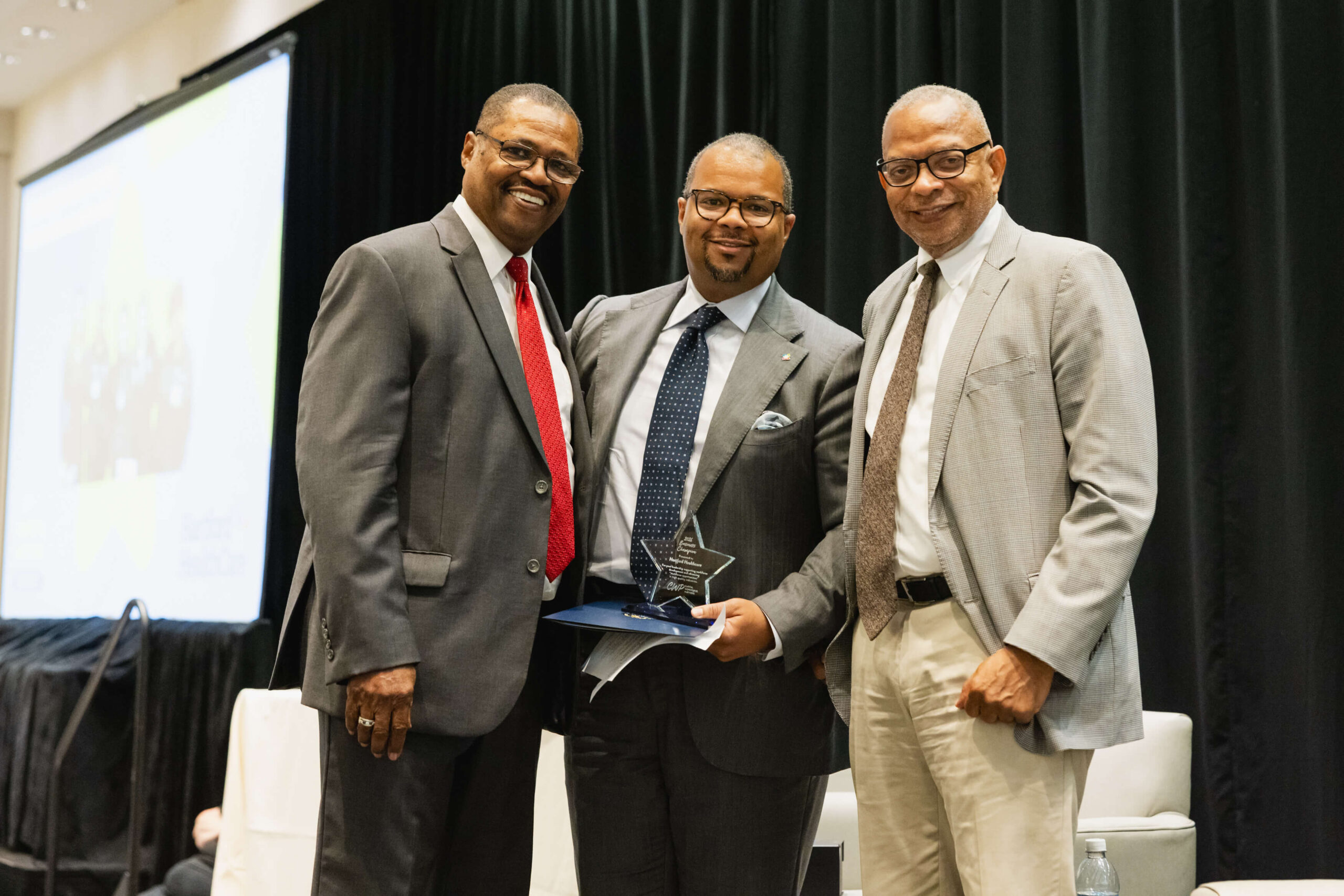 Hartford Healthcare representative accepting award at 2026 CWP Annual Meeting with CWP leadership by his side.